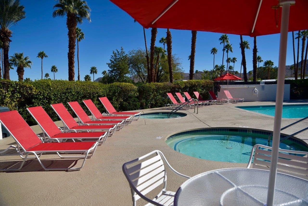 Resort pool and lounge area surrounded by palm trees and mountains